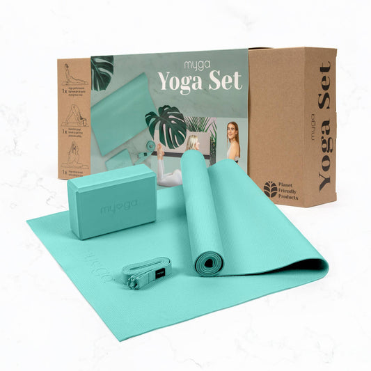 The Myga 3-piece Yoga Set in teal/mint green is displayed in front of its cardboard retail box. The set includes a rolled yoga mat, a foam yoga block, and a yoga strap, highlighting a complete, planet-friendly yoga accessory kit.