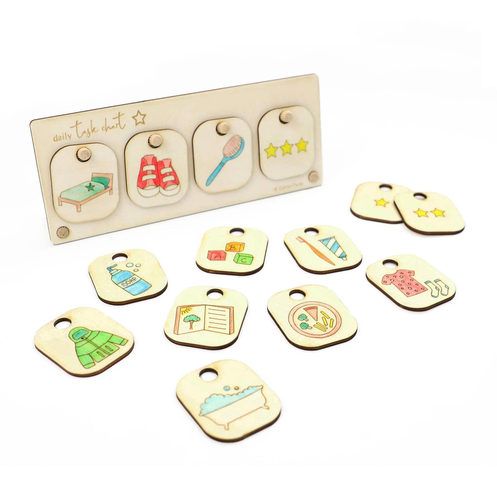 Wooden DIY Daily Task Chart or Chore Board set. The display shows four task slots, and seven interchangeable task tokens are scattered below, illustrating chores like making the bed, brushing teeth, reading a book, eating a meal, tidying toys, and taking a bath. The set includes reward stars.