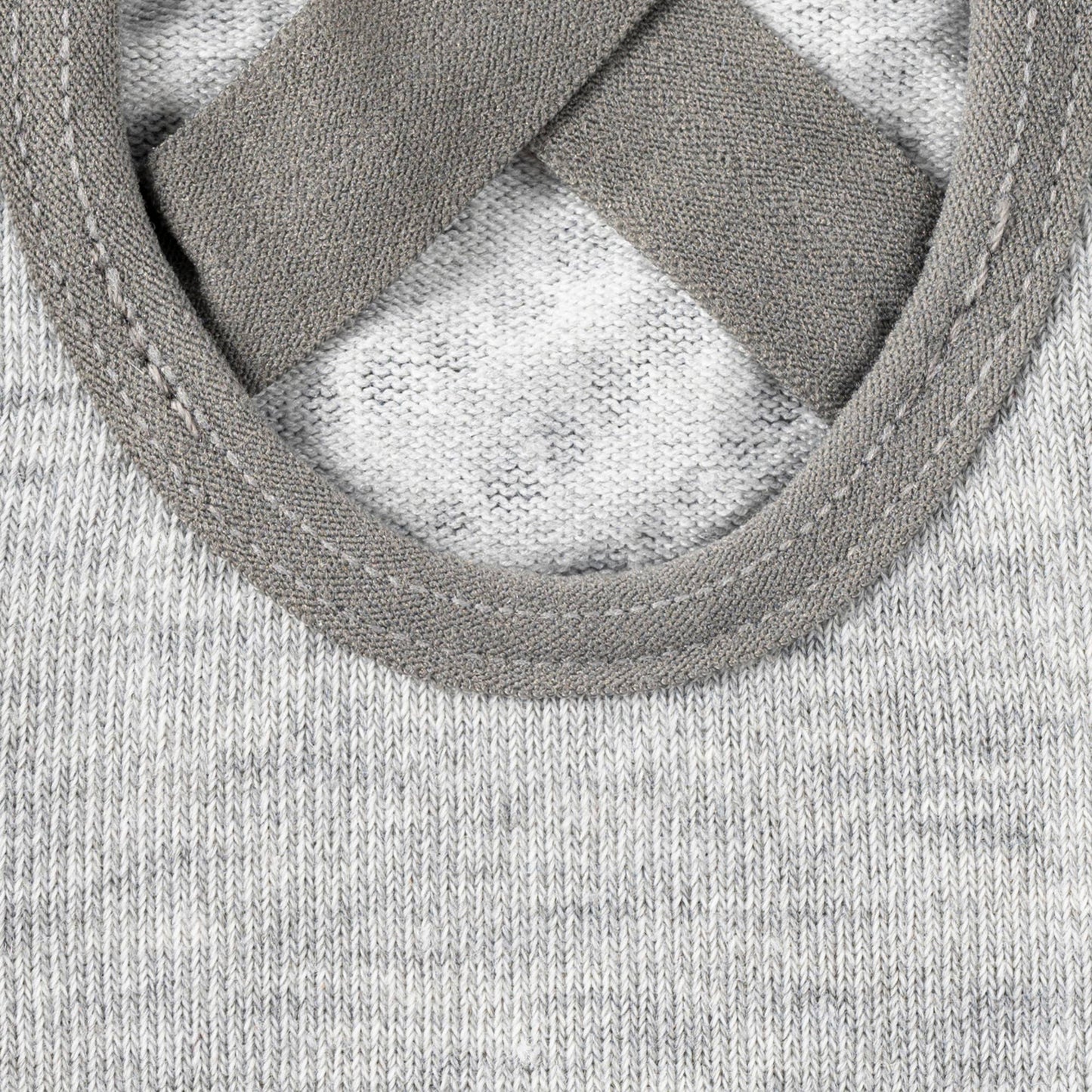 Extreme close-up on the grey fabric of a non-slip sock, focusing on the detail of the criss-cross elastic straps and the stitching around the open arch cutout, highlighting the secure fit design.