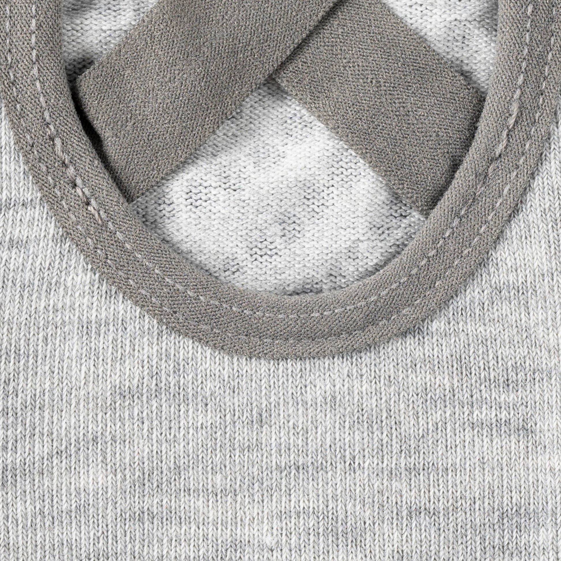 Extreme close-up on the grey fabric of a non-slip sock, focusing on the detail of the criss-cross elastic straps and the stitching around the open arch cutout, highlighting the secure fit design.