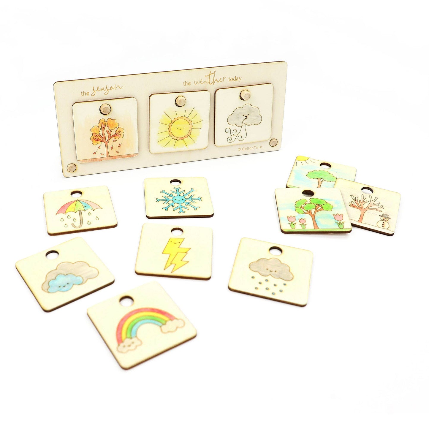 Full set of the color-in wooden weather and season chart. The display stand shows Autumn/Fall, Sunny, and Cloudy tags. Spread below are all the interchangeable tokens, including Winter/Snowflake, Summer/Sun, Spring/Tree, Rainbow, Rain, Lightning, and Umbrella tags.