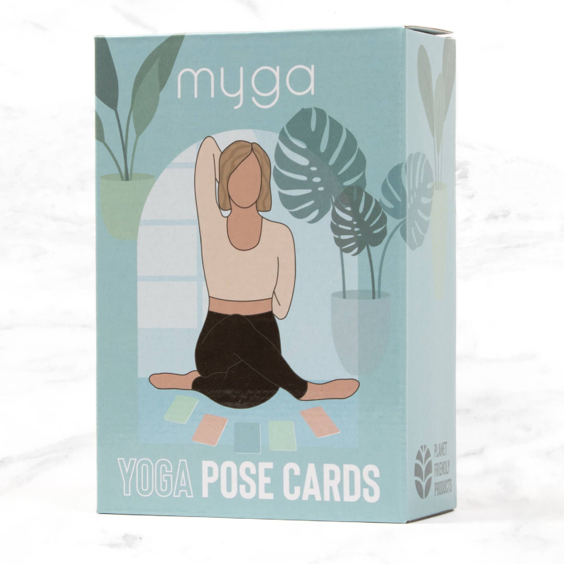 Retail box for Myga Yoga Pose Cards. The light blue packaging features an illustration of a person doing a seated yoga pose (Modified Half Lord of the Fishes Pose) surrounded by houseplants. The box is labeled 'YOGA POSE CARDS' and 'PLANT FRIENDLY PRODUCT.'