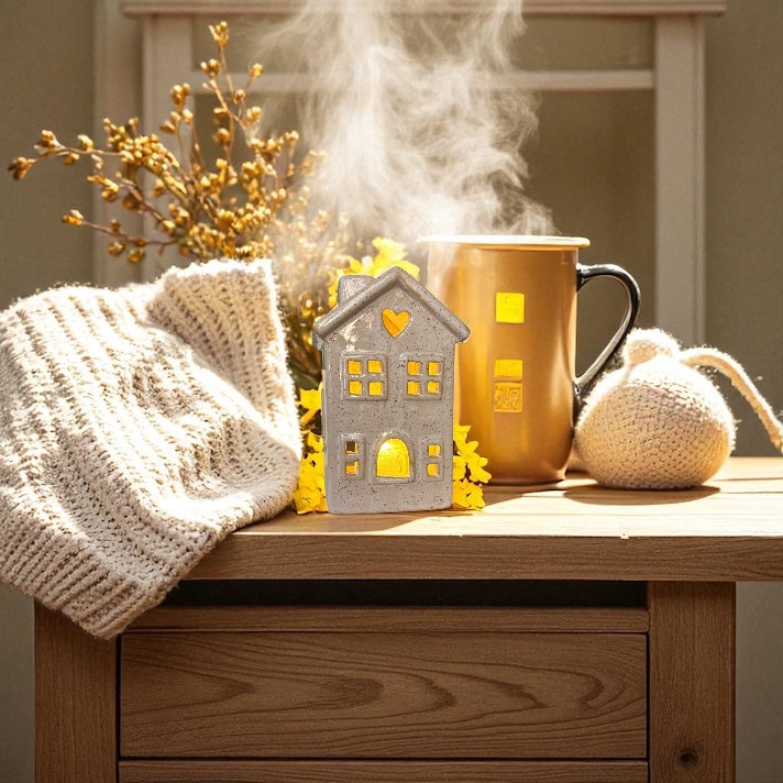 Ceramic candle holder on a bedside table, next to a throw and hot drink. 